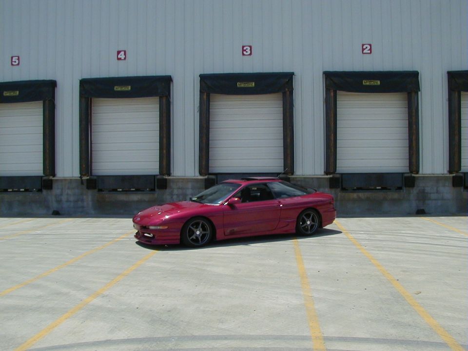 Red 1994 Ford Probe parked in front of loading docks