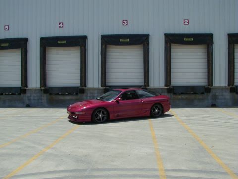 1994 Ford Probe - A red 1994 Ford Probe is parked outside a warehouse with multiple loading bay doors.