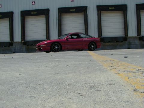 1994 Ford Probe - A red coupe is parked in front of a row of industrial loading bay doors.