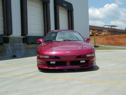 1994 Ford Probe - Front view of a red 1994 Ford Probe parked outside a building with yellow lines on the ground.