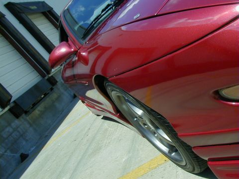 1994 Ford Probe - Side view of a red car, focusing on the front wheel and fender area.