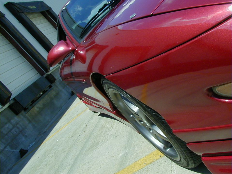 Red car side view, showing front wheel and fender