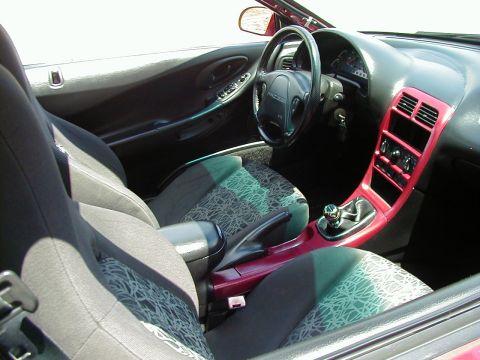 1994 Ford Probe - The interior of a red car features patterned seats and a distinctive red trim around the center console and dashboard.