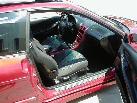 1994 Ford Probe - Interior view of a red car with the driver's door ajar, revealing the seats and dashboard.