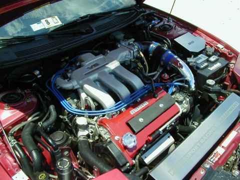 1994 Ford Probe - Close-up view of a red Mazda engine bay, highlighting the V6 intake manifold and blue spark plug wires.