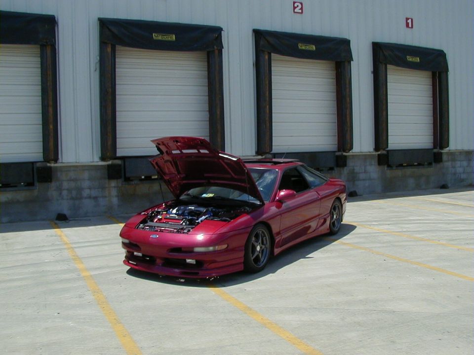 Red coupe with hood open, parked in front of loading docks