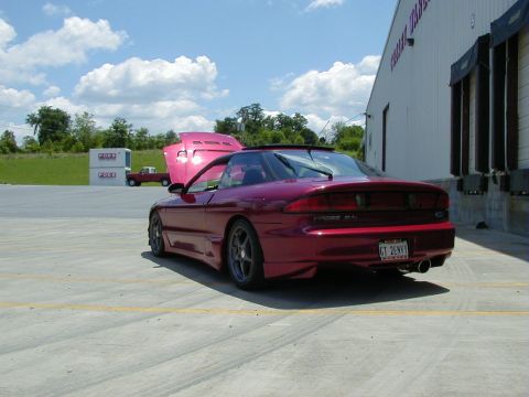 1994 Ford Probe - A red Ford Probe is parked outside a warehouse with its hood open, showing off its engine bay.
