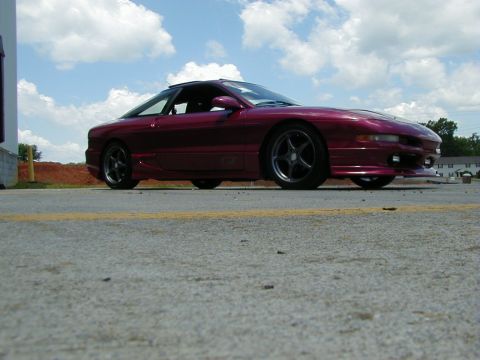 1994 Ford Probe - A red 1994 Ford Probe is captured in a 3/4 front view, parked on asphalt under a cloudy sky.