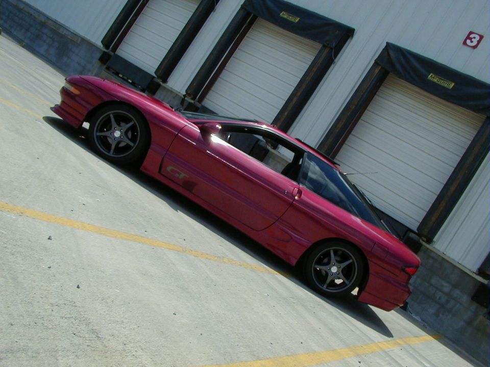 Red 1994 Ford Probe GT parked outside a warehouse with loading docks