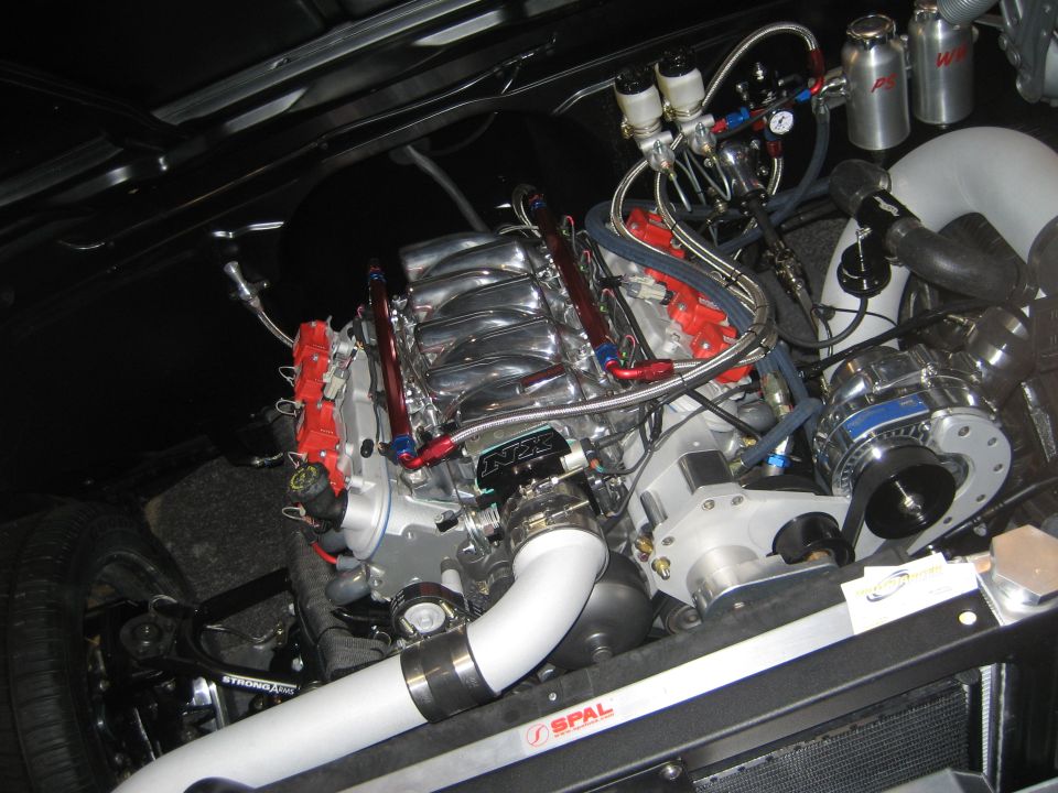 Supercharged V8 engine in black engine bay with red intake and SPAL fan