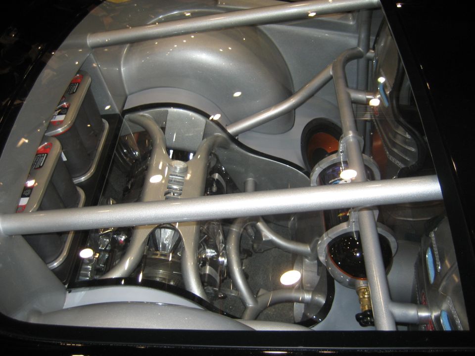 Mid-engine bay under glass with tubular bracing and silver bodywork
