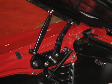 1998 Ford Crown Victoria - Close-up of custom hood hinges and gas struts on a red vehicle.