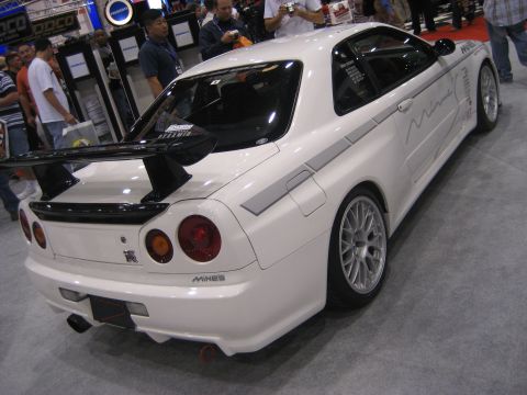 1998 Ford Crown Victoria - Rear view of a modified white Nissan Skyline GT-R R34 with aftermarket wheels and a large rear spoiler.
