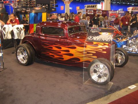 1998 Ford Crown Victoria - Custom hot rod coupe with flame paint job on display at an indoor event.