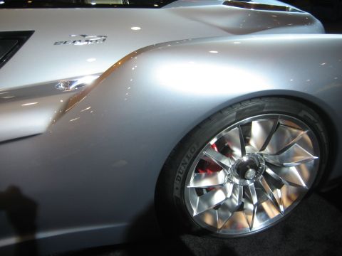 1998 Ford Crown Victoria - A silver car is shown from the side, distinctive chrome wheels and visible red brake calipers.