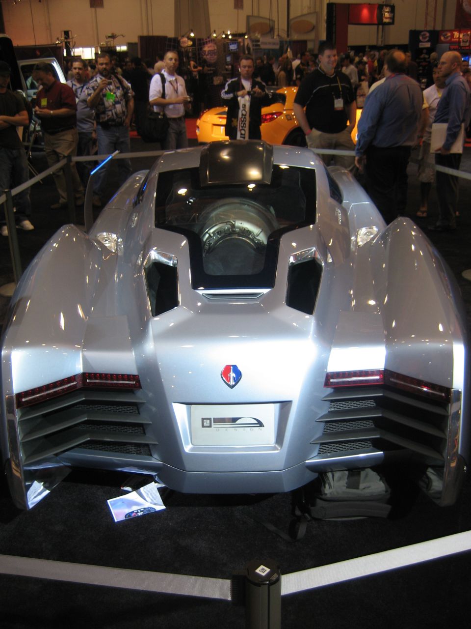 Rear view of a silver jet-style concept car with center canopy at a show