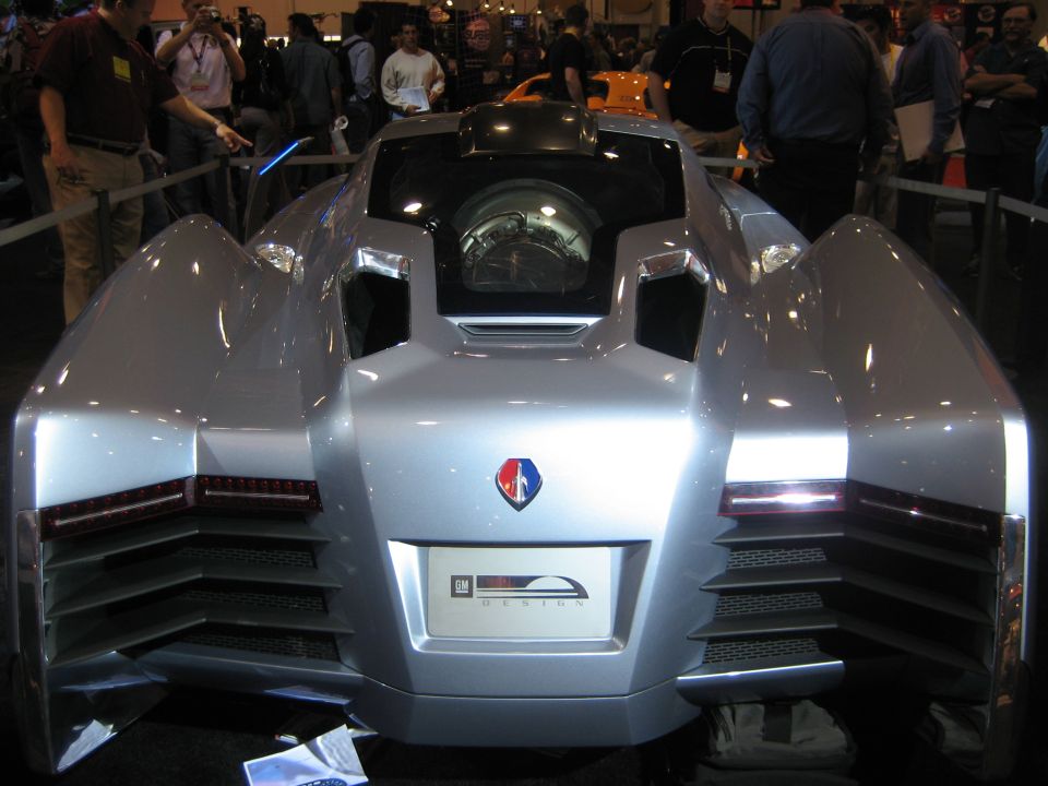 Rear view of silver GM Design concept car with central canopy at a show