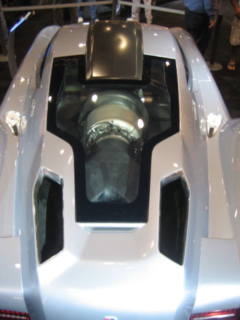 1998 Ford Crown Victoria - A silver sports car displays its engine through a glass panel on its rear deck.