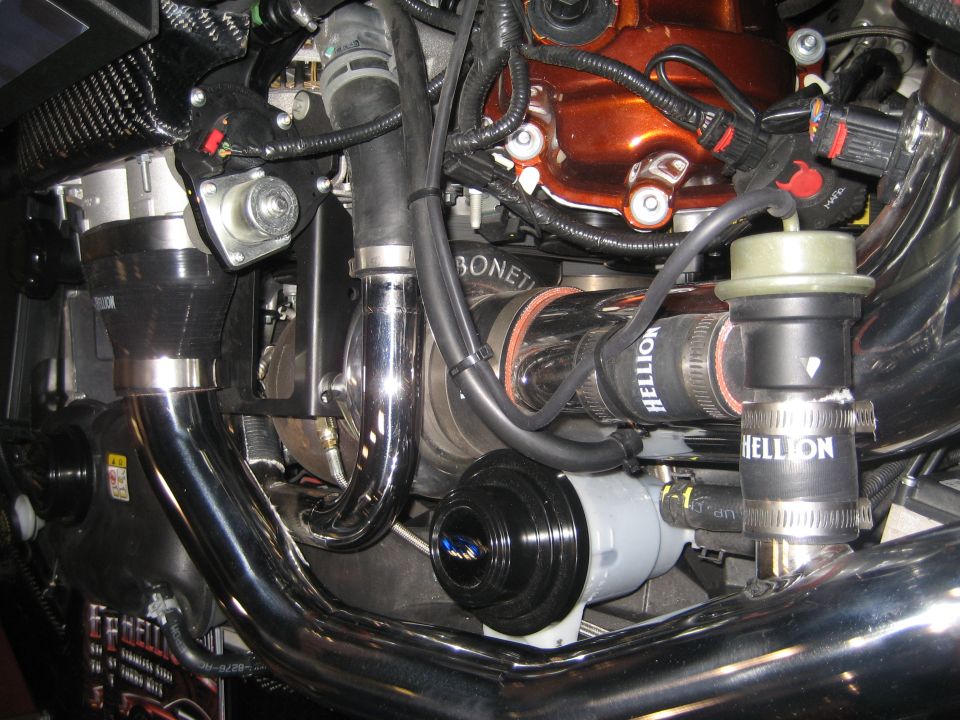 Close-up of an engine bay with Hellion-branded turbo plumbing and hoses