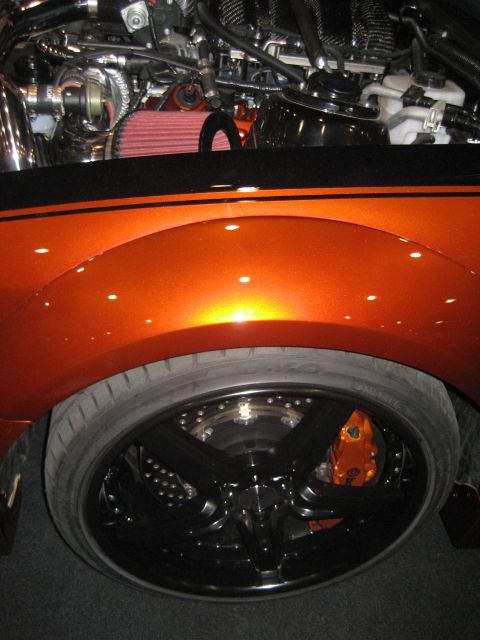 1998 Ford Crown Victoria - Close-up of a modified car's engine and wheel assembly, custom orange paint and performance parts.