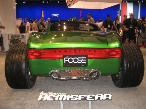 1998 Ford Crown Victoria - A custom green car with oversized rear tires is displayed at an auto show.