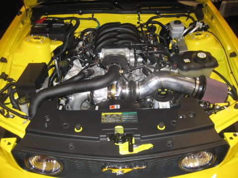 1998 Ford Crown Victoria - Aftermarket turbocharger system installed in a yellow vehicle's engine bay.