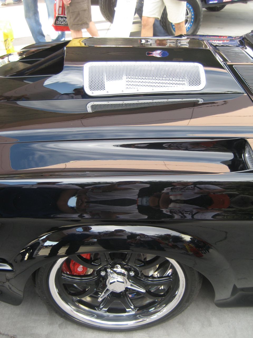 Glossy black custom car hood vent and fender over a chrome five-spoke wheel