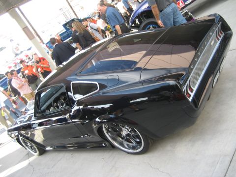 1998 Ford Crown Victoria - A crowd gathers around a heavily modified black coupe at an outdoor event.