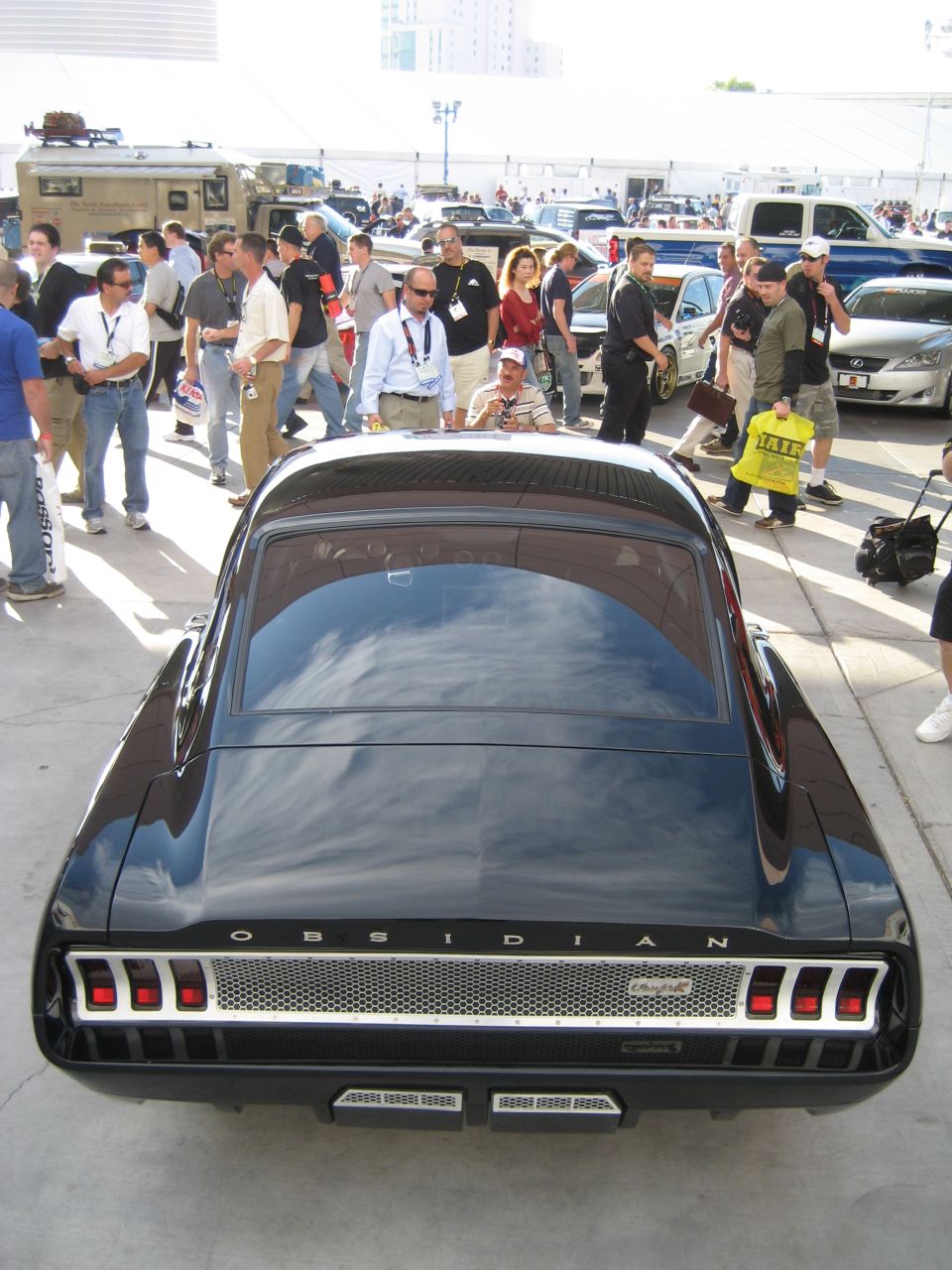 Overhead rear view of black OBSIDIAN fastback coupe surrounded by show crowd
