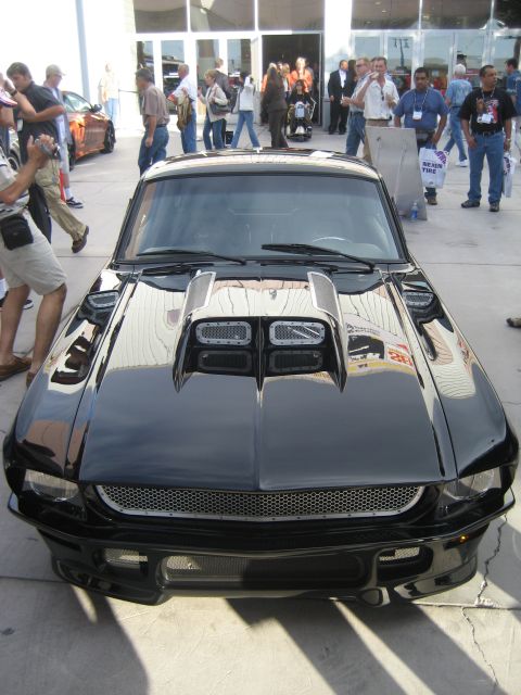 1998 Ford Crown Victoria - Front view of a modified black 1967 Ford Mustang with a prominent hood scoop.