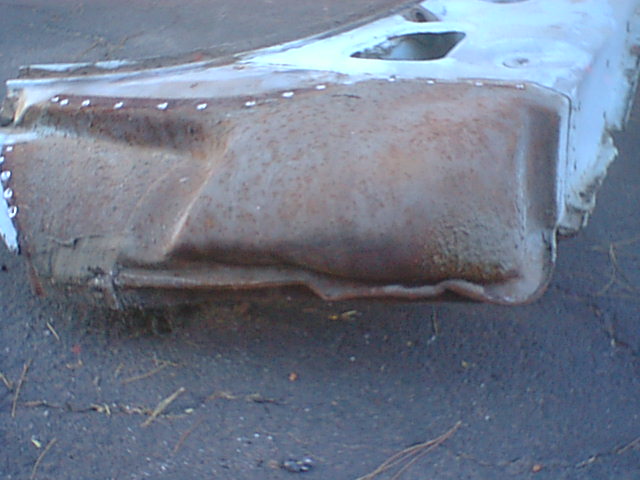Rusty white-painted automotive sheet-metal panel section lying on pavement