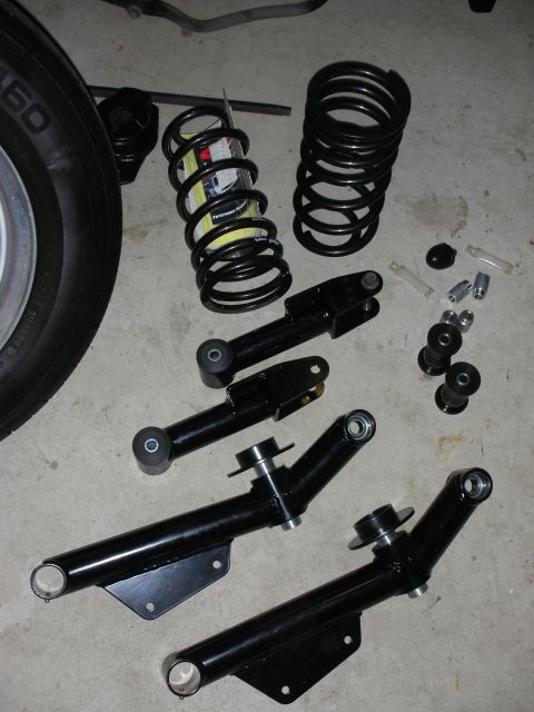 1990 Ford Mustang - Various black suspension components, including control arms and coil springs, are laid out on a concrete surface.