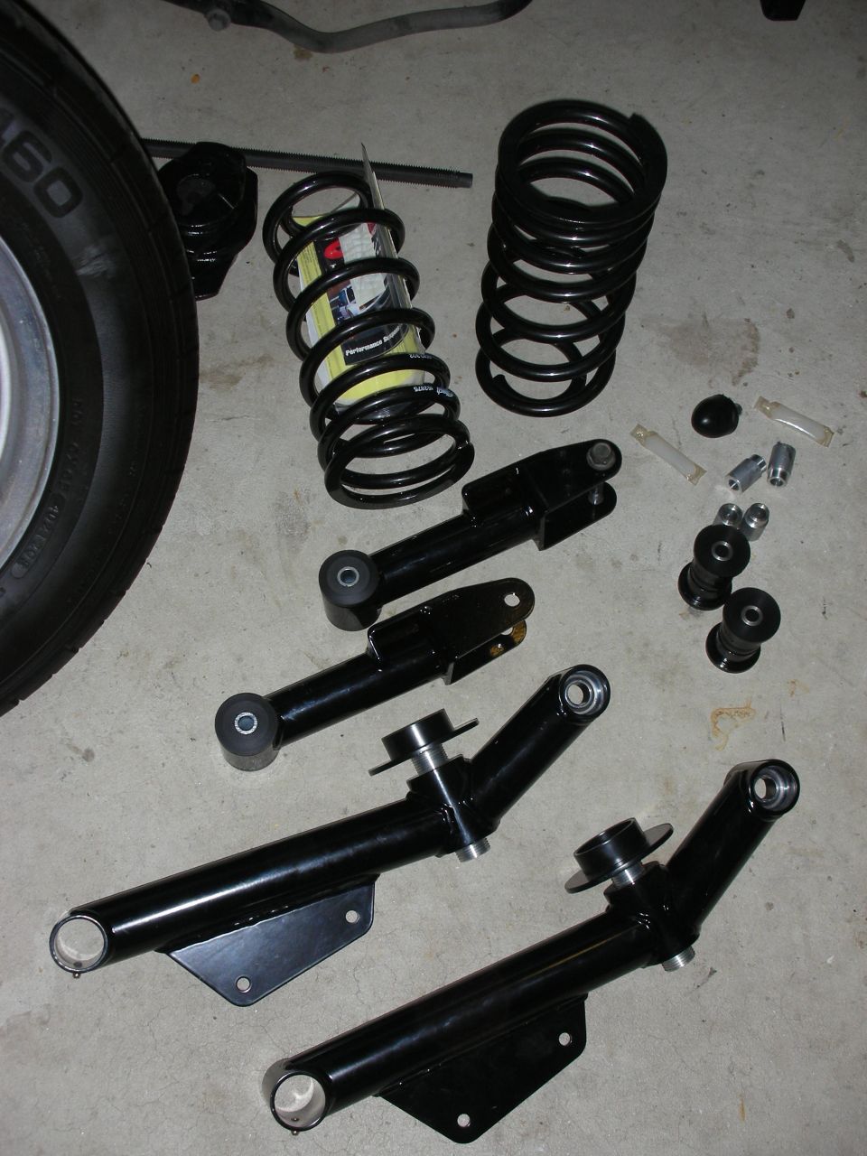 Black suspension control arms and coil springs on a concrete floor