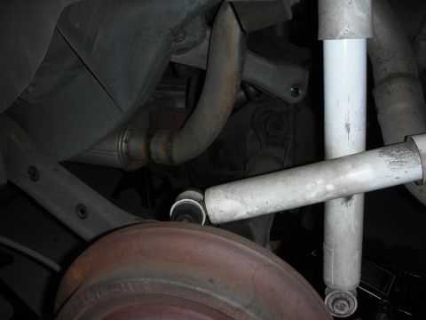 1990 Ford Mustang - Close-up view of the rear suspension system, showing the shock absorber, brake drum, and exhaust pipe.