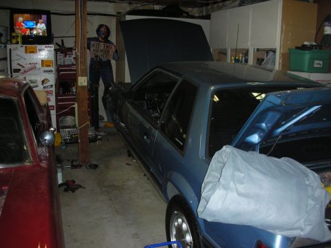 1990 Ford Mustang - Two cars, a blue 1990 Ford Mustang and a red car, are parked in a garage with their hoods open.