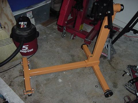 1984 BMW 3 Series - An orange engine stand and a red 5-gallon shop vac are visible on a concrete floor with other garage equipment.