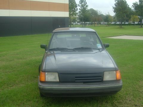 1989 Ford Escort - This car appears to be a hatchback from the late 1980s, possibly a Ford Escort, but the exact model year is unclear from the image.