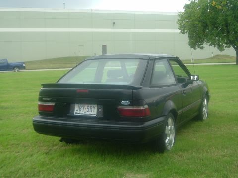 1989 Ford Escort - Rear view of a black 1989 Ford Escort hatchback with a spoiler and aftermarket wheels.