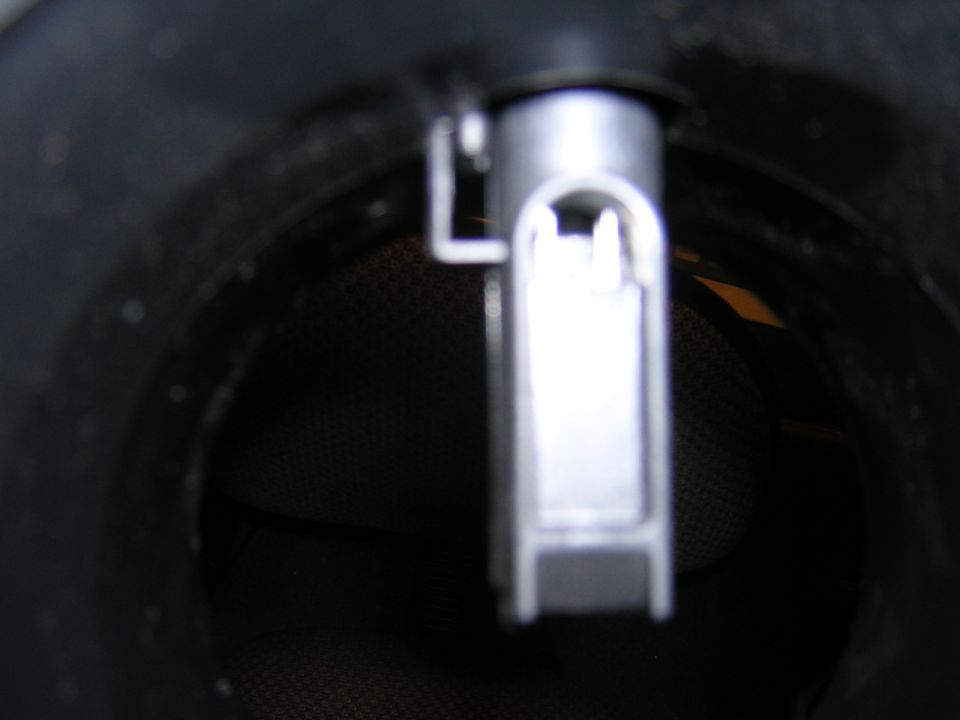 Close-up through a dark tube at an unidentified bright metal blade-shaped piece