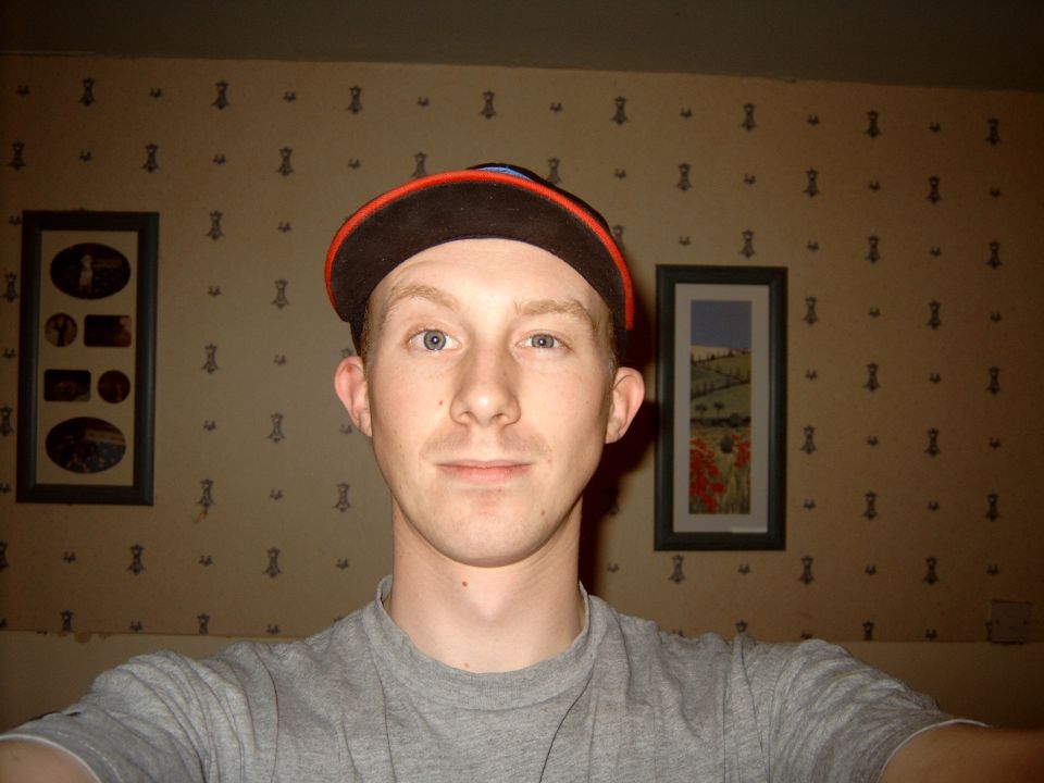 Young man wearing a backwards ball cap taking a selfie indoors