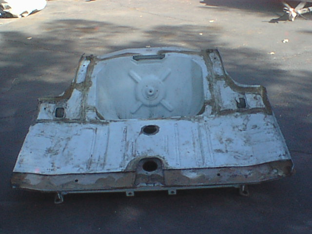 Underside of a vehicle rear floor pan with spare tire well on pavement