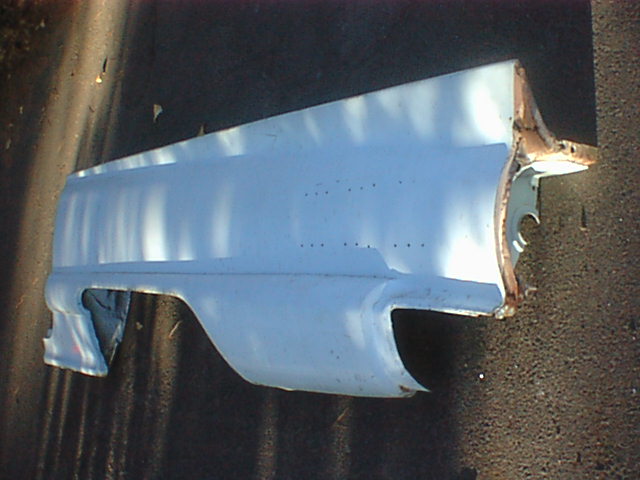 Light blue / primed front fender panel with bondo seams lying on the ground