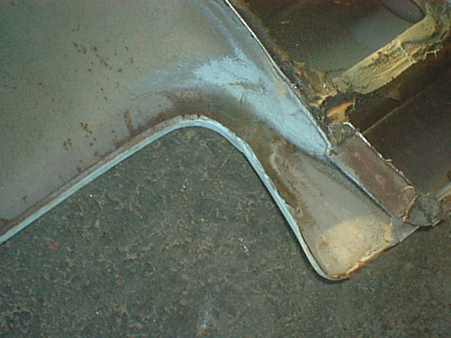Rusty inner fender sheet-metal panel section on pavement