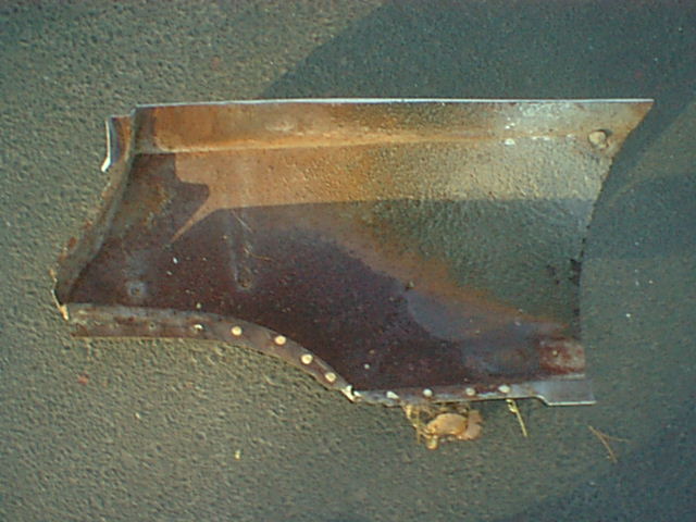 Rusty curved lower fender or quarter panel section on ground