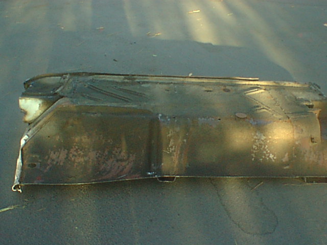 Long rusty ribbed floor pan panel on pavement