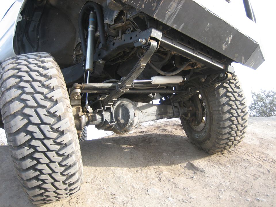 Rear leaf spring suspension and large tire on a white SUV with aftermarket bumper