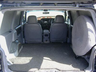 2000 Jeep Cherokee - The interior of a 2000 Jeep Cherokee van is viewed from the rear, revealing the cargo space and front seating area.