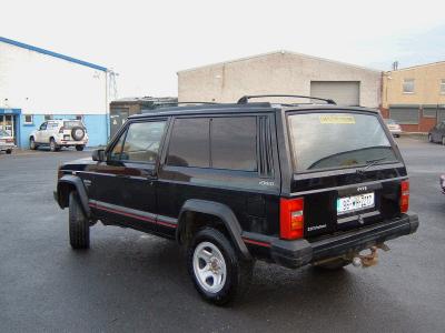 2000 Jeep Cherokee - This black 2000 Jeep Cherokee is seen from the rear 3/4 angle in a commercial area.