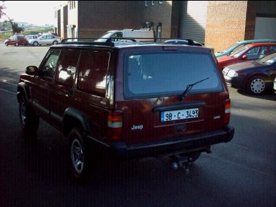 2000 Jeep Cherokee - A maroon 2000 Jeep Cherokee is parked outdoors, with other vehicles visible in the background.