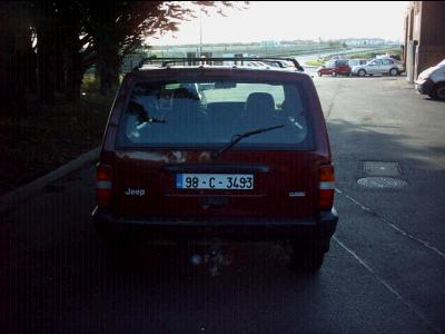 2000 Jeep Cherokee - Rear view of a red Jeep Cherokee, identified by its distinctive XJ body style. The license plate reads 98-C-3493.